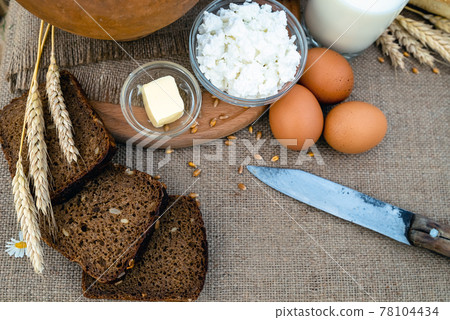 Organic food - milk, bread, eggs, cheese, butter, knife, lying on the table, against the background 78104434