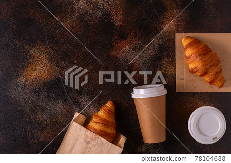 Coffee to go in a paper cup with croissants. Coffee to go in a paper cup with croissants. 78104688
