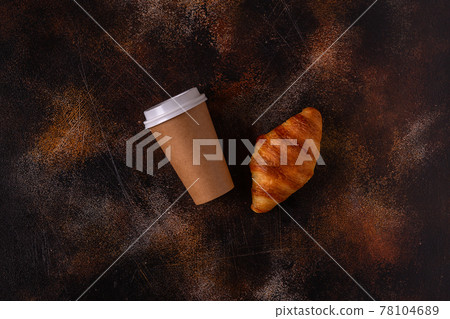 Coffee to go in a paper cup with croissants. Coffee to go in a paper cup with croissants. 78104689
