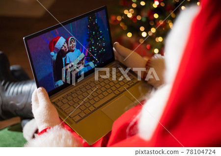 Happy mom and son talking to santa claus by video chat on a laptop. Woman and boy remotely wishes Merry Christmas Happy mom and son talking to santa claus by video chat on a laptop. Woman and boy remotely wishes Merry Christmas 78104724