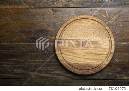 Empty round cutting board on a wooden table. Space for text. 78104973