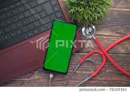 Medical Stethoscope and smart phone on laptop on wooden table  78105361