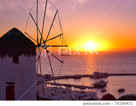 Famous traditional Greek windmill, Mykonos, Greece against sunset and sea. Beautiful sky, sun touch sea horizon, colorful image, selective focus 78106472