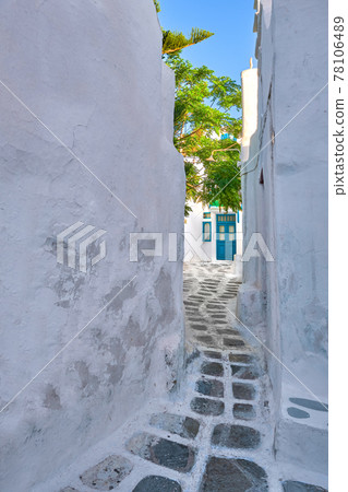 Traditional narrow cobblestone streets, beautiful alleyways of Greek island towns. Whitewashed walls, houses, blue doors. Summer. Mykonos, Greece 78106489