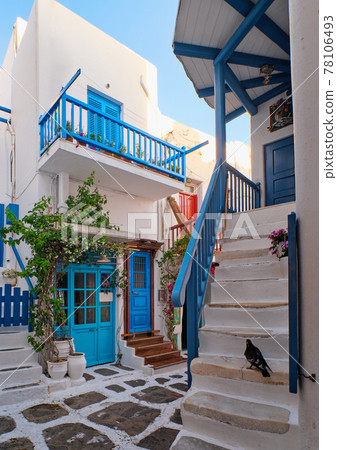 Traditional narrow cobbled streets, beautiful alleyways of Greek island towns. White houses, flower pots, blue balconies and doors. Mykonos, Greece 78106493