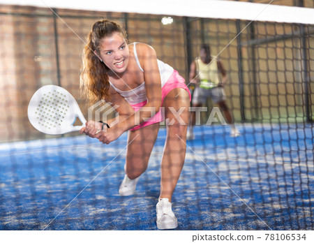 Young beautiful woman with racket playing padel 78106534