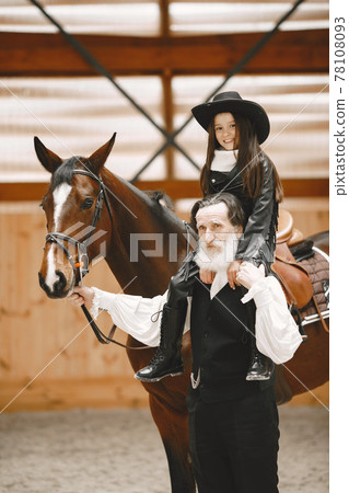 A little child riding a horse with an instructor 78108093