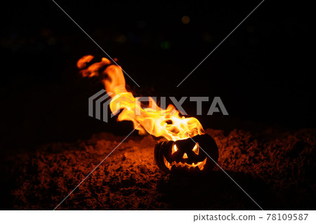 Tongues of flame in a pumpkin. jack-o-lantern on fire on a black background. Halloween symbol on the ground. Trick or treat. Close up. Tongues of flame in a pumpkin. jack-o-lantern on fire on a black background. Halloween symbol on the ground. Trick or treat. Close up. 78109587
