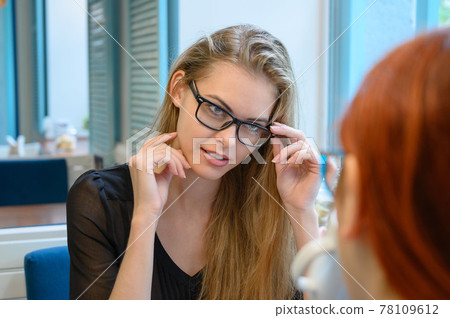 Not a traditional couple. A young blonde is flirting with her girlfriend in a cafe. A gay woman looks at her partner with a seductive look. LGBT community. Not a traditional couple. A young blonde is flirting with her girlfriend in a cafe. A gay woman looks at her partner with a seductive look. LGBT community. 78109612