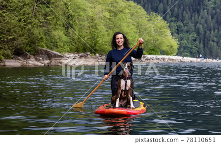 Adult Caucasian Adventure Woman on a paddle board with boxer dog 78110651