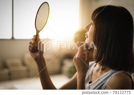 Woman looking in the mirror 78112775