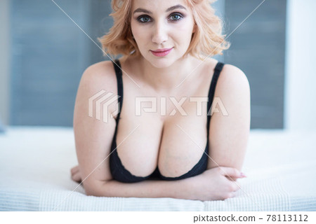 A European girl with a cute face and big Breasts in black underwear lies on her stomach. Very sexy. 78113112