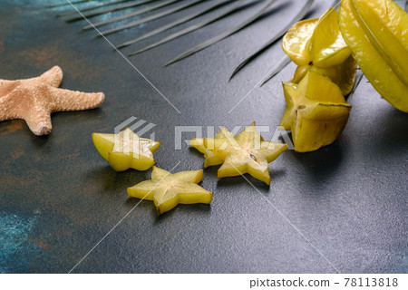 Fruit carambol, beach accessories and foliage of a tropical plant on colored paper 78113818