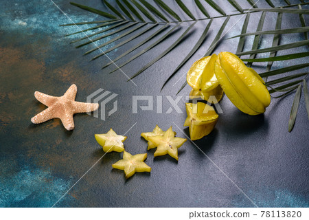 Fruit carambol, beach accessories and foliage of a tropical plant on colored paper Fruit carambol, beach accessories and foliage of a tropical plant on colored paper 78113820