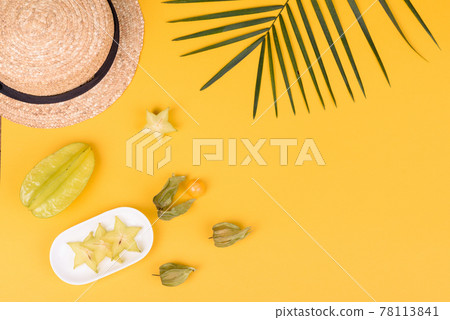 Fruit carambol, beach accessories and foliage of a tropical plant on colored paper 78113841