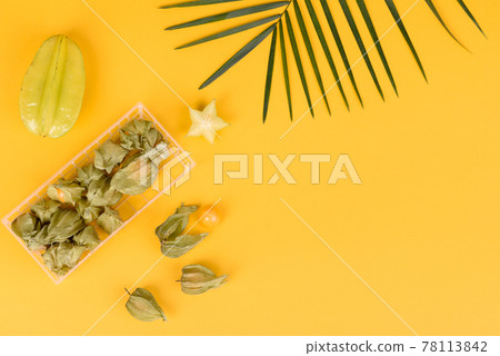 Fruit carambol, beach accessories and foliage of a tropical plant on colored paper 78113842