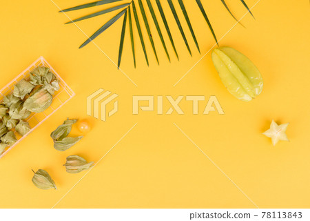 Fruit carambol, beach accessories and foliage of a tropical plant on colored paper 78113843