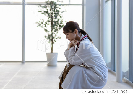 Female doctor crouching in the hospital Female doctor crouching in the hospital 78115043