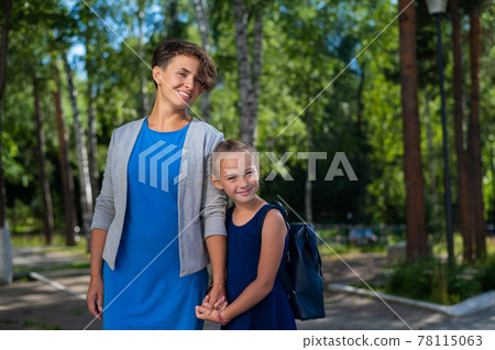 A Caucasian woman with short hair holds her daughter, a schoolgirl, by the hand 78115063