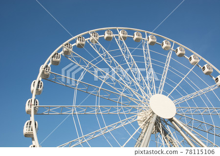 Part of a white Ferris wheel against a blue sky in summer day. 78115106