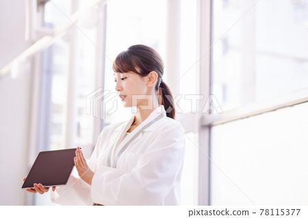 一名醫務工作者婦女向框架外的人展示平板電腦終端的屏幕 78115377
