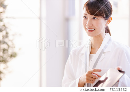 一名醫務工作者婦女向框架外的人展示平板電腦終端的屏幕 78115382