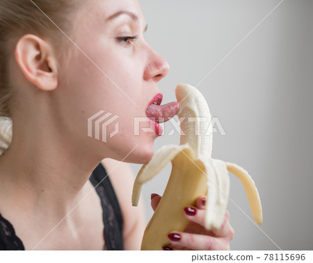 A blonde in black lace lingerie seductively sucks and licks a banana. Woman with sensual red imitates oral pleasure. A blonde in black lace lingerie seductively sucks and licks a banana. Woman with sensual red imitates oral pleasure. 78115696