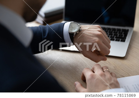 Punctual businessman checking time at workplace, consulting luxury wristwatch 78115869