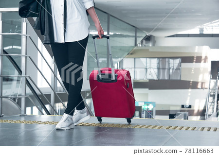 woman traveler with luggage in the airport or train station; legs and suitcase close-up woman traveler with luggage in the airport or train station; legs and suitcase close-up 78116663