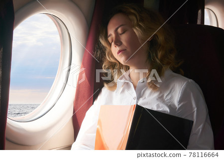 young woman dozed off in the cabin of an airplane flying low above the sea surface, or some high-speed vessel 78116664