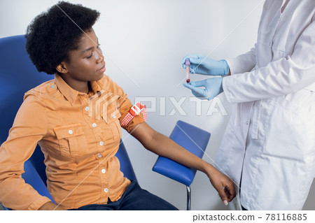 Healthy lifestyle, regular check up, blood analysis. Close up portrait of pretty young African woman, sitting in blue chair at modern lab. Lab technician nurse holding in hands test tube with blood. 78116885