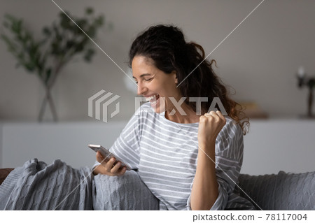 Excited Hispanic woman triumph reading news on cell 78117004