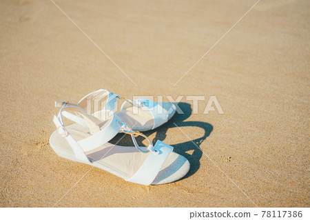 Sandals placed on the sandy beach 78117386
