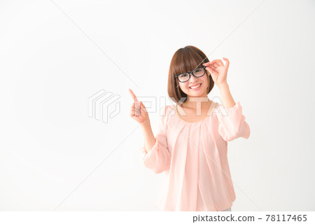 A smiling young woman with glasses pointing her finger 78117465