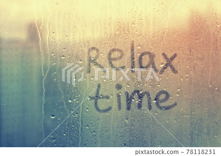 Foggy glass on window with written finger word relax time on muddy blue glass wet orange window in city on sunset Foggy glass on window with written finger word relax time on muddy blue glass wet orange window in city on sunset 78118231