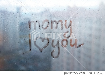 Foggy glass on window with written finger word momy i love you with heart shape on blue overcast wet window 78118232