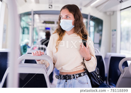 Portrait of a focused girl in a protective mask riding on public transport Portrait of a focused girl in a protective mask riding on public transport 78118899