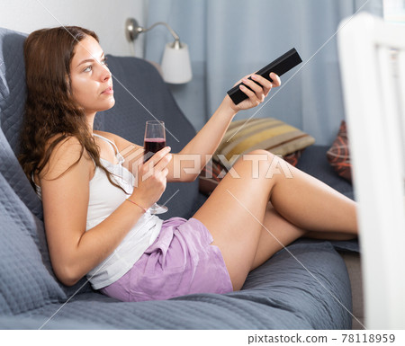 Woman drinking wine watching TV at home 78118959