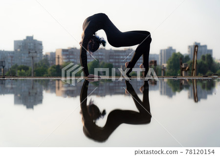 Silhouette of flexible and fit girl bending her back. Concept of yoga and healthy lifestyle Silhouette of flexible and fit girl bending her back. Concept of yoga and healthy lifestyle 78120154