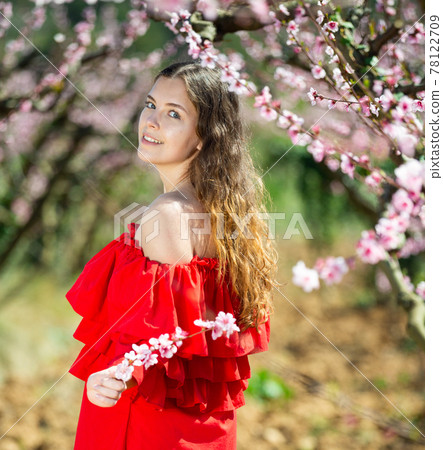Cheerful girl posing in a red dress in spring blooming garde 78122709