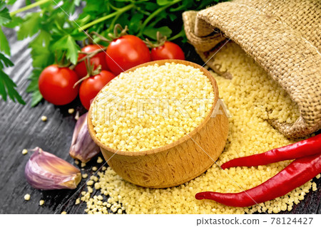 Couscous raw in bowl on dark wooden board Couscous raw in bowl on dark wooden board 78124427