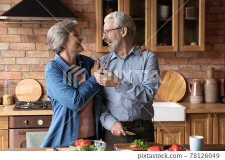 Joyful mature couple of vegans cooking dinner together at home 78126049