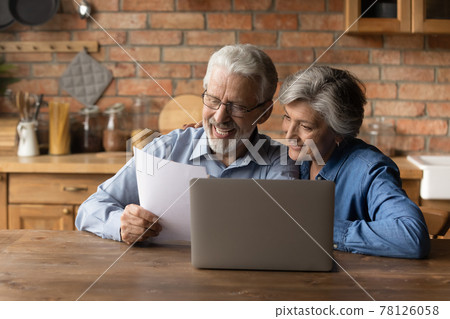 Happy middle aged couple reading good news in document Happy middle aged couple reading good news in document 78126058