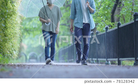 Mask couple walking in the fresh green on a rainy day Mask couple walking in the fresh green on a rainy day 78128342