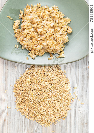 pile of raw whole oat grains and boiled porridge 78128901