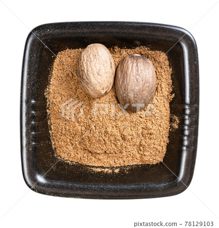 whole nutmeg seeds and powder in black bowl whole nutmeg seeds and powder in black bowl 78129103
