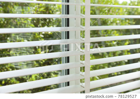 Sunlight coming through venetian blinds by the window . Sunlight coming through venetian blinds by the window . 78129527