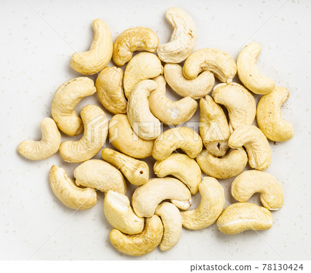 pile of raw cashew seeds close up on gray 78130424