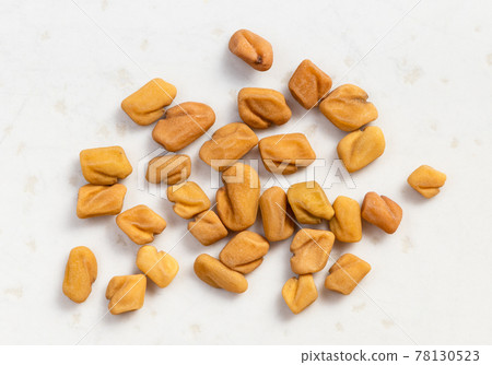 several whole fenugreek seeds close up on gray 78130523