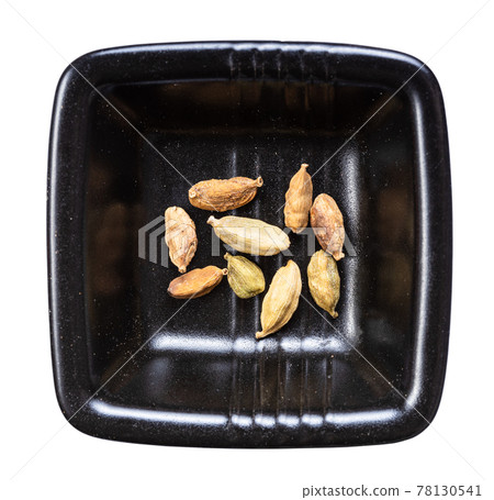 several cardamom pods in black bowl isolated several cardamom pods in black bowl isolated 78130541